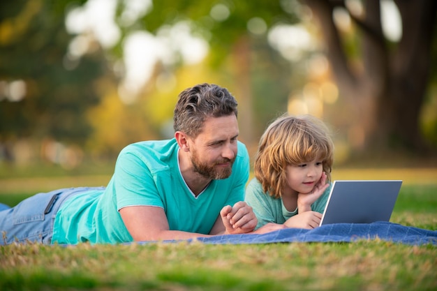 Blogging glücklicher Vater mit Laptop entspannen sich mit Schulsohn mit Laptop Kindheit und Elternschaft k ...