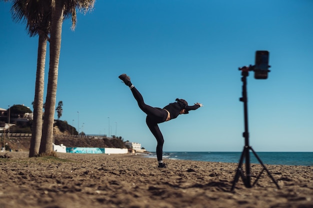 Blogueando estilo de vida joven bloguera atractiva en ropa deportiva graba video en su teléfono