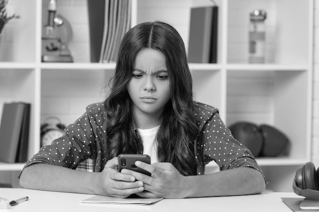 Blogueira adolescente séria de tecnologia de comunicação moderna usa smartphone de volta à escola