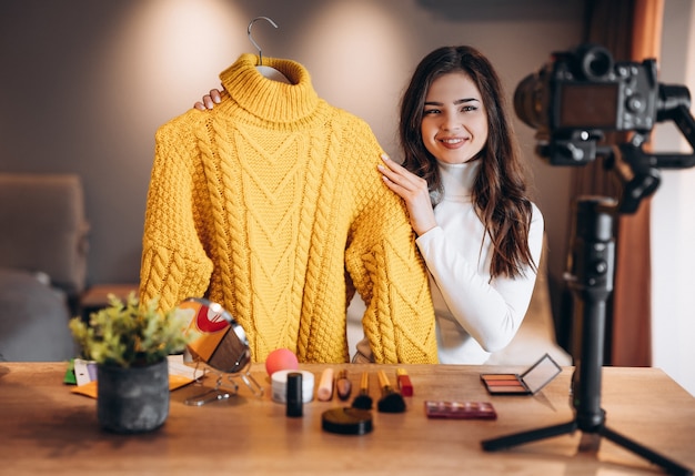 Blogueira de beleza doce feminino filmando tutorial de rotina de maquiagem diária na câmera. avaliação de produtos cosméticos de transmissão ao vivo de jovem influente em um estúdio caseiro. trabalho de vlogger. mostrando roupas. lookbook.