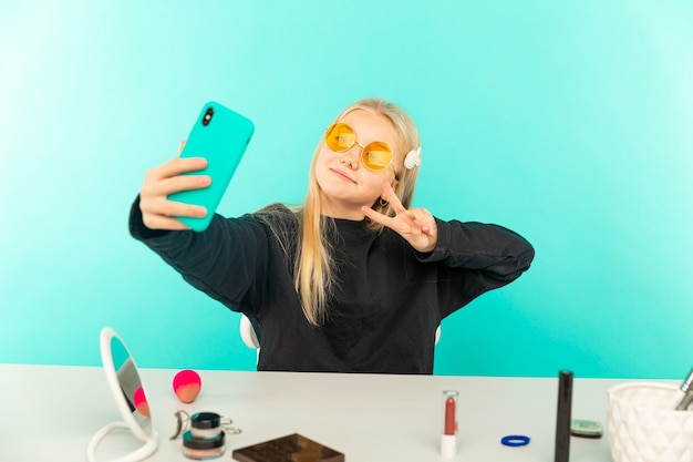 Blogueira de beleza feminina. adolescente loira posando para a câmera e fazendo um vlog.