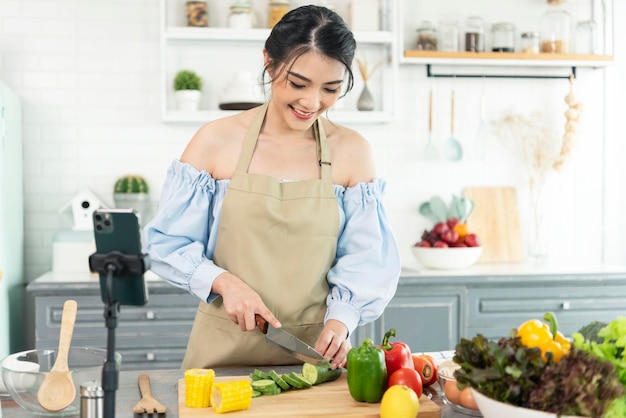 Blogueira de comida asiática cozinhando salada na frente da câmera do smartphone enquanto grava o vídeo do vlog