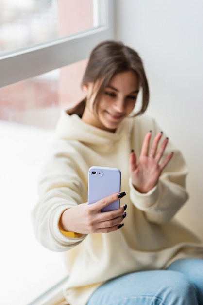 Blogueira feliz tirando retrato selfie na câmera do smartphone para mídia social postando adolescente alegre falando em videochamada com a família ou amigos via telefone celularFoco seletivo suave