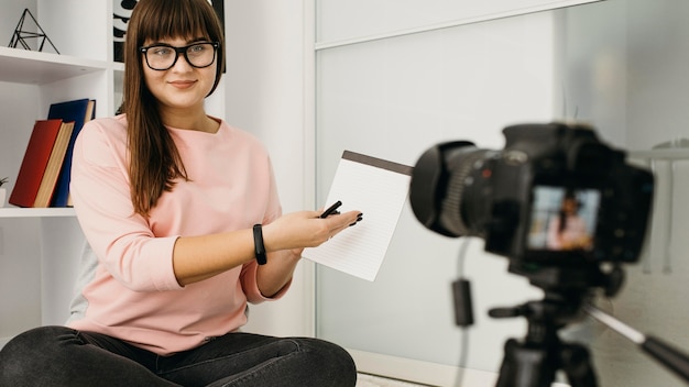 Blogueira feminina fazendo streaming em casa com câmera e notebook