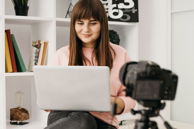 Foto blogueira feminina fazendo streaming em casa com laptop e câmera