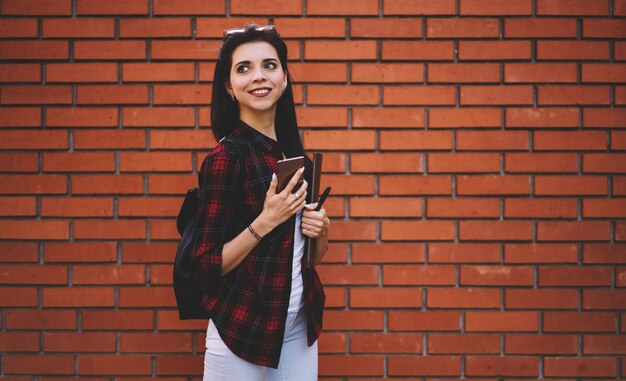 Blogueiro de menina alegre sorridente com cabelo moreno usando smartphone para conversar com seguidores