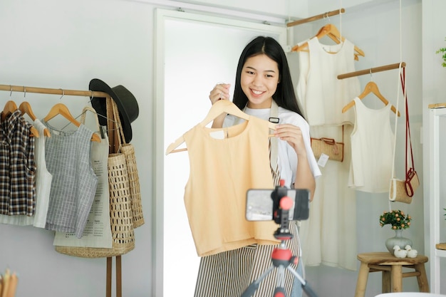 Blogueiro de moda jovem empresária asiática mostrando pano com rosto sorridente