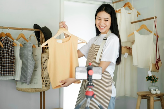 Blogueiro de moda jovem empresária asiática mostrando pano com rosto sorridente