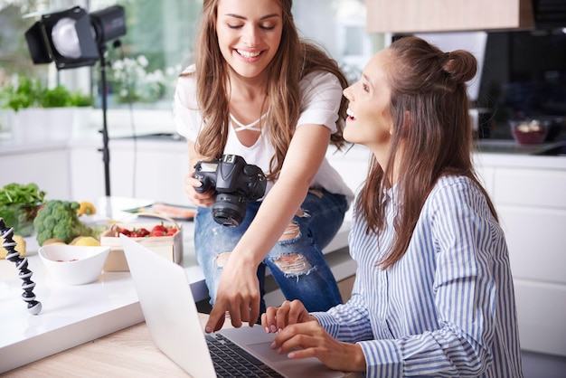 Blogueiros felizes usando laptop na cozinha