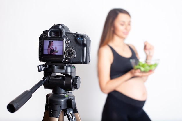 Una bloguera embarazada graba un video en cámara sobre una nutrición adecuada durante el embarazo