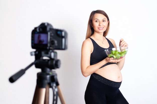 Una bloguera embarazada graba un video en cámara sobre una nutrición adecuada durante el embarazo