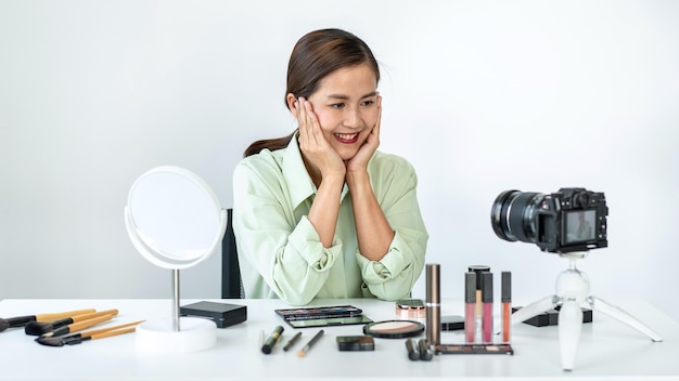 Foto una bloguera muestra un tutorial de maquillaje actual, un producto de revisión cosmética de belleza y transmite videos en vivo a la red social enseñando en línea en la pantalla de la cámara