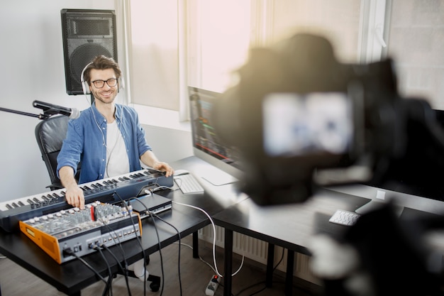 El bloguero de video en vivo enseña cómo hacer pistas de música en vivo. Video para red social o transmisión. DJ en estudio de radiodifusión. El productor musical está componiendo una canción en el estudio de grabación.