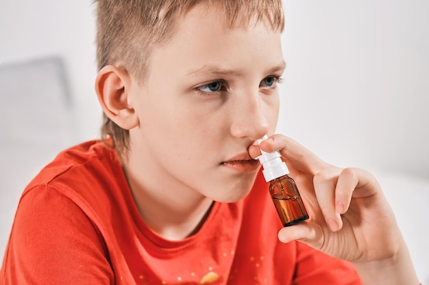 Blond Boy tropft Nasentropfen aus laufender Nase Behandlung von Erkältungen und allergischer Rhinitis Selektiver Fokus