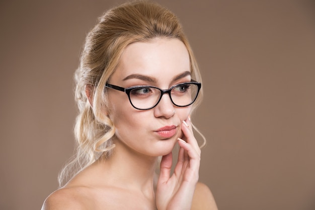 Blond mit der Hand in der Nähe der Lippen