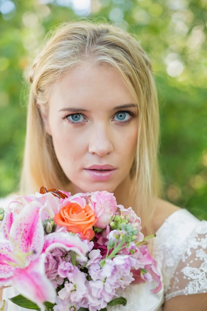 Foto blonde braut, welche die kamera hält blumenstrauß betrachtet