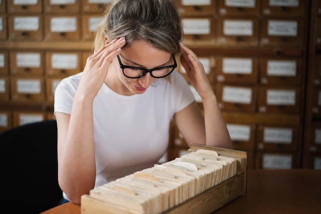 Blonde Frau, die Buchdateien in der Bibliothek sucht