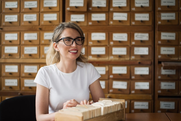 Blonde Frau, die Buchdateien in der Bibliothek sucht