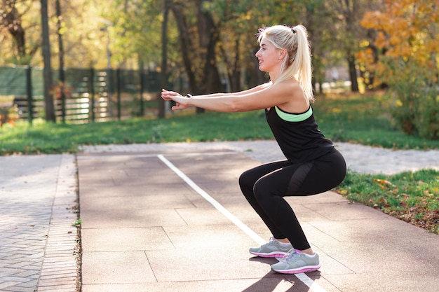 Blonde Frau, die draußen Hocken tut