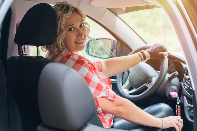 Blonde Frau, die ein Auto mit Schaltgetriebe fährt