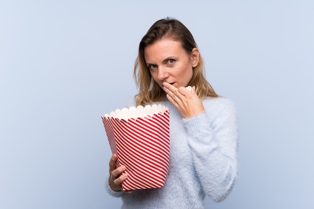 Blonde Frau, die einen großen Eimer Popcorn hält