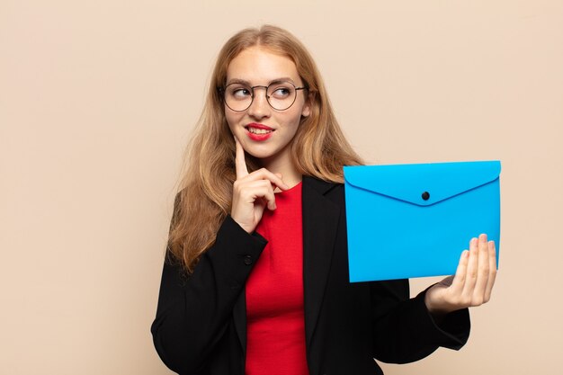 Blonde Frau, die glücklich lächelt und Tagträumen oder Zweifel hat und zur Seite schaut