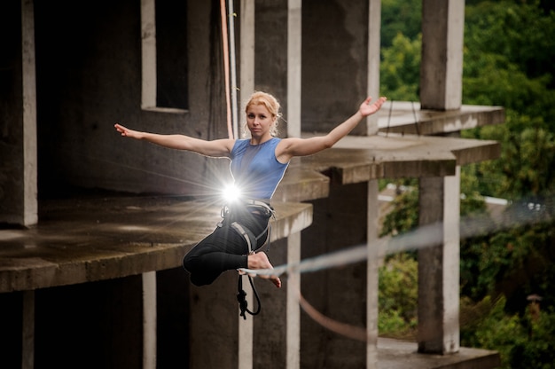 Blonde Frau, die hoch auf einer Slackline balanciert