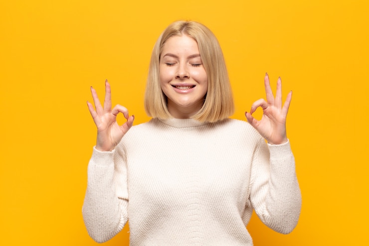Foto blonde frau, die konzentriert und meditierend aussieht, sich zufrieden und entspannt fühlt, denkt oder eine wahl trifft