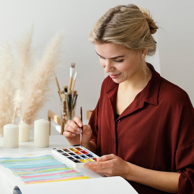 Foto blonde frau, die mit aquarellen malt