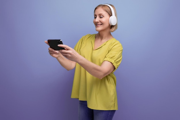 Blonde Frau, die mit Kopfhörern Sendungen auf dem Smartphone ansieht