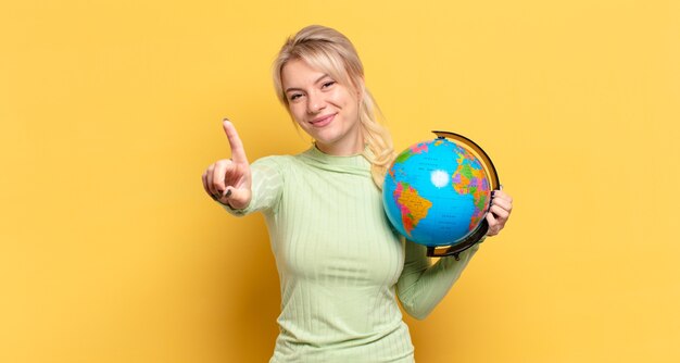 Blonde Frau, die stolz und selbstbewusst lächelt und die Nummer eins triumphierend posiert und sich wie eine Anführerin fühlt