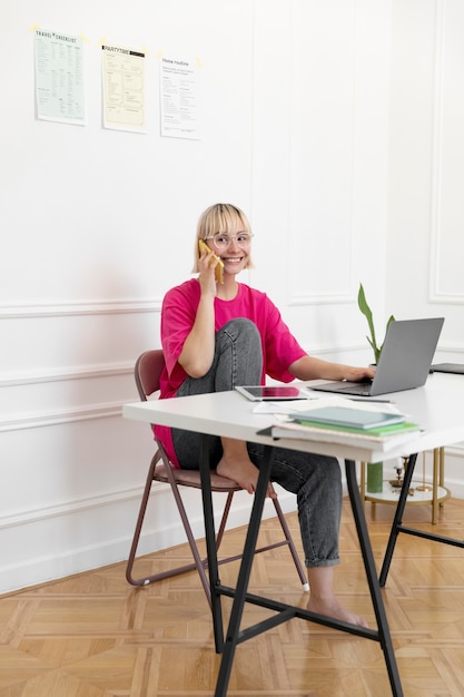 Blonde Frau, die von zu Hause aus an ihrem Laptop arbeitet