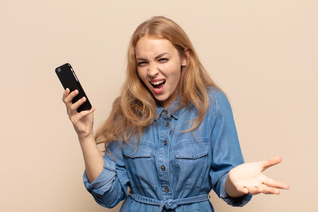 Blonde Frau, die wütend, genervt und frustriert aussieht und wtf schreit oder was mit dir los ist