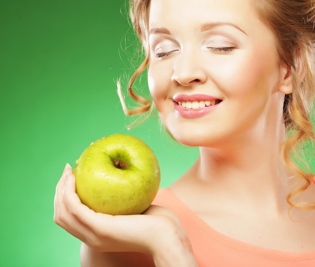 Blonde Frau essen grünen Apfel über grünem Hintergrund