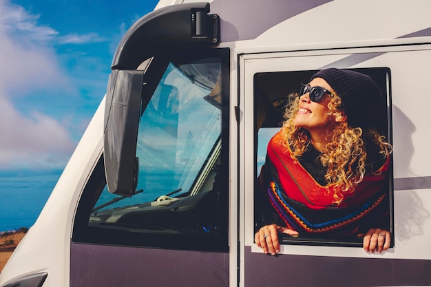 Blonde Frau fährt einen geparkten Wohnwagen und genießt den Blick auf eine wunderschöne Landschaft mitten in der Natur Konzept der Freiheit und Urlaub