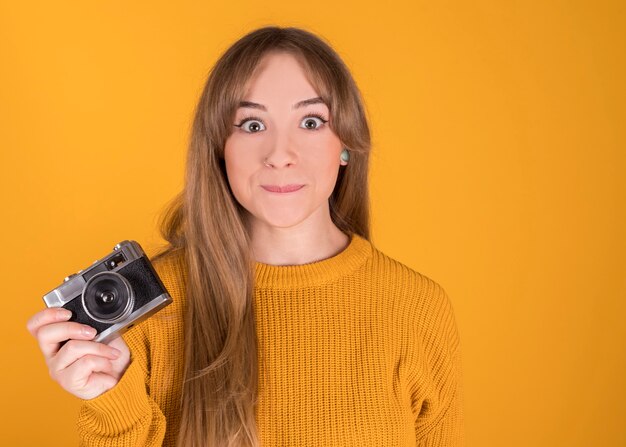 Blonde Frau hält eine Fotokamera mit ausdrucksstarkem Gesicht