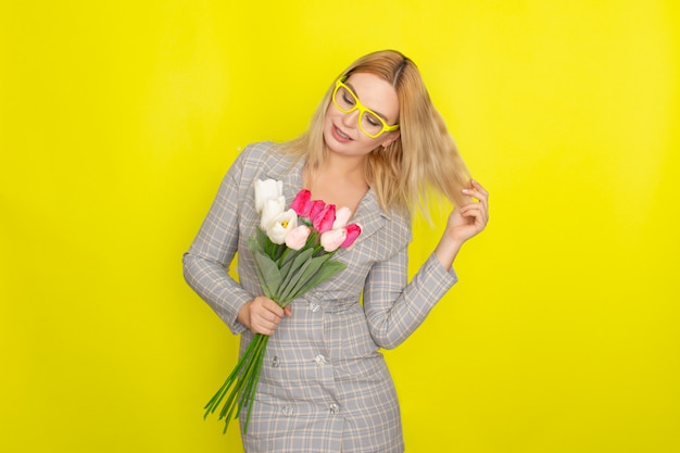 Blonde Frau im karierten Kleid, das Tulpenstrauß hält