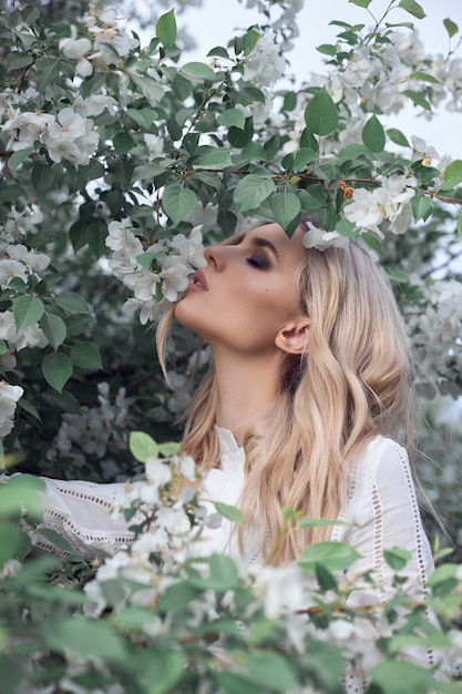 blonde Frau im Sommer in den Zweigen eines Apfelbaums