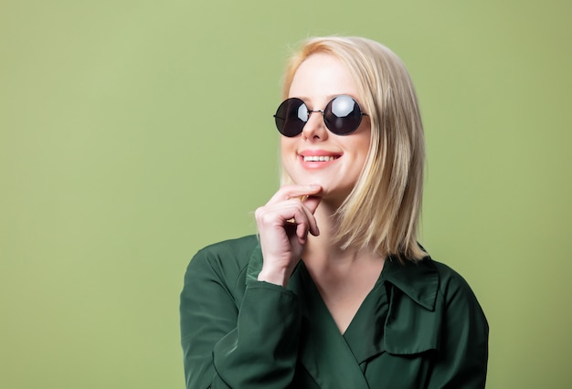 Blonde Frau im Umhang und in der runden Sonnenbrille