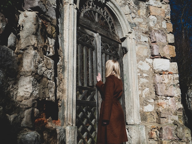 Blonde Frau in der Nähe von Ruinen der alten Tür in einem Schloss