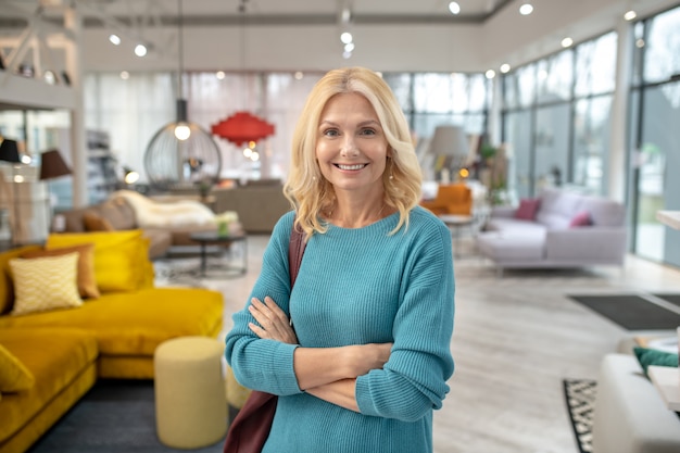 Blonde Frau in einem blauen Kleid, das schön lächelt