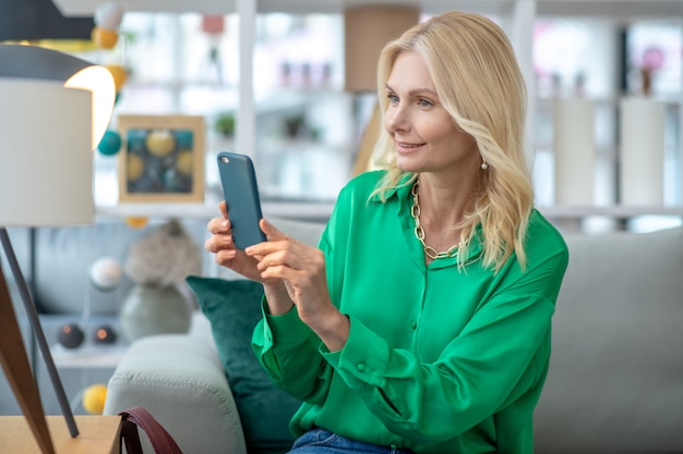 Blonde Frau in einer grünen Bluse, die ein Bild macht