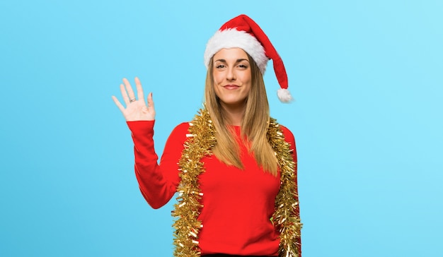 Blonde Frau kleidete oben für die Weihnachtsfeiertage an, die mit der Hand mit glücklichem Ausdruck begrüßen