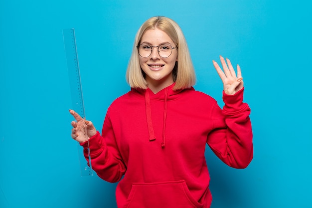 Blonde Frau lächelt und sieht freundlich aus, zeigt Nummer vier oder vierten mit der Hand nach vorne, Countdown