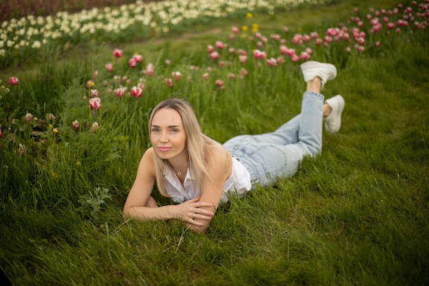 Blonde Frau liegt mit Tulpen auf dem Gras