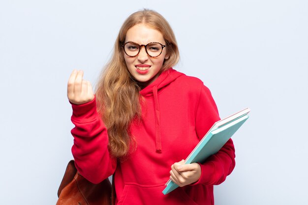 Blonde Frau macht Capice oder Geldgeste und sagt dir, du sollst deine Schulden bezahlen!