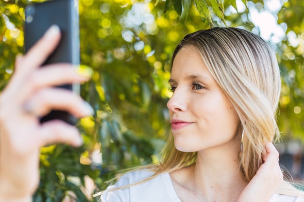 Blonde Frau macht ein Selfie im Freien. Wellness-, Natur- und Outdoor-Konzept.