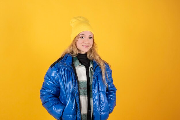 Blonde Frau mit blauer Freizeitkleidung und gelbem Hut