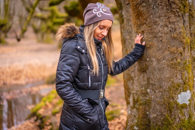 blonde Frau mit einem langen Mantel in einem Wald