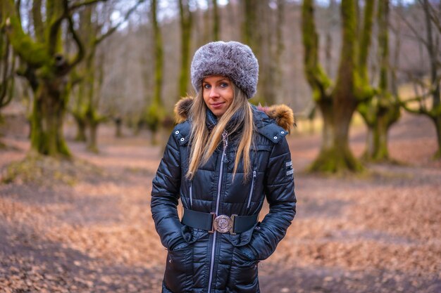 blonde Frau mit einem langen Mantel in einem Wald